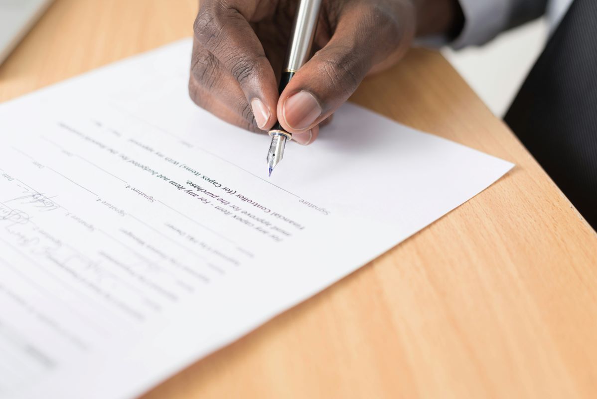 A hand holding pen while signing document